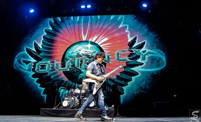 Neal Schon Plays Guitar against a Turqiouse Backdrop Variety of Images